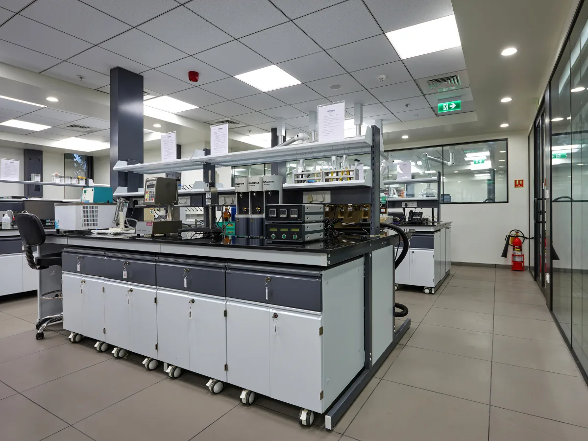 Central island bench with analytical instruments and glass-partitioned corridors