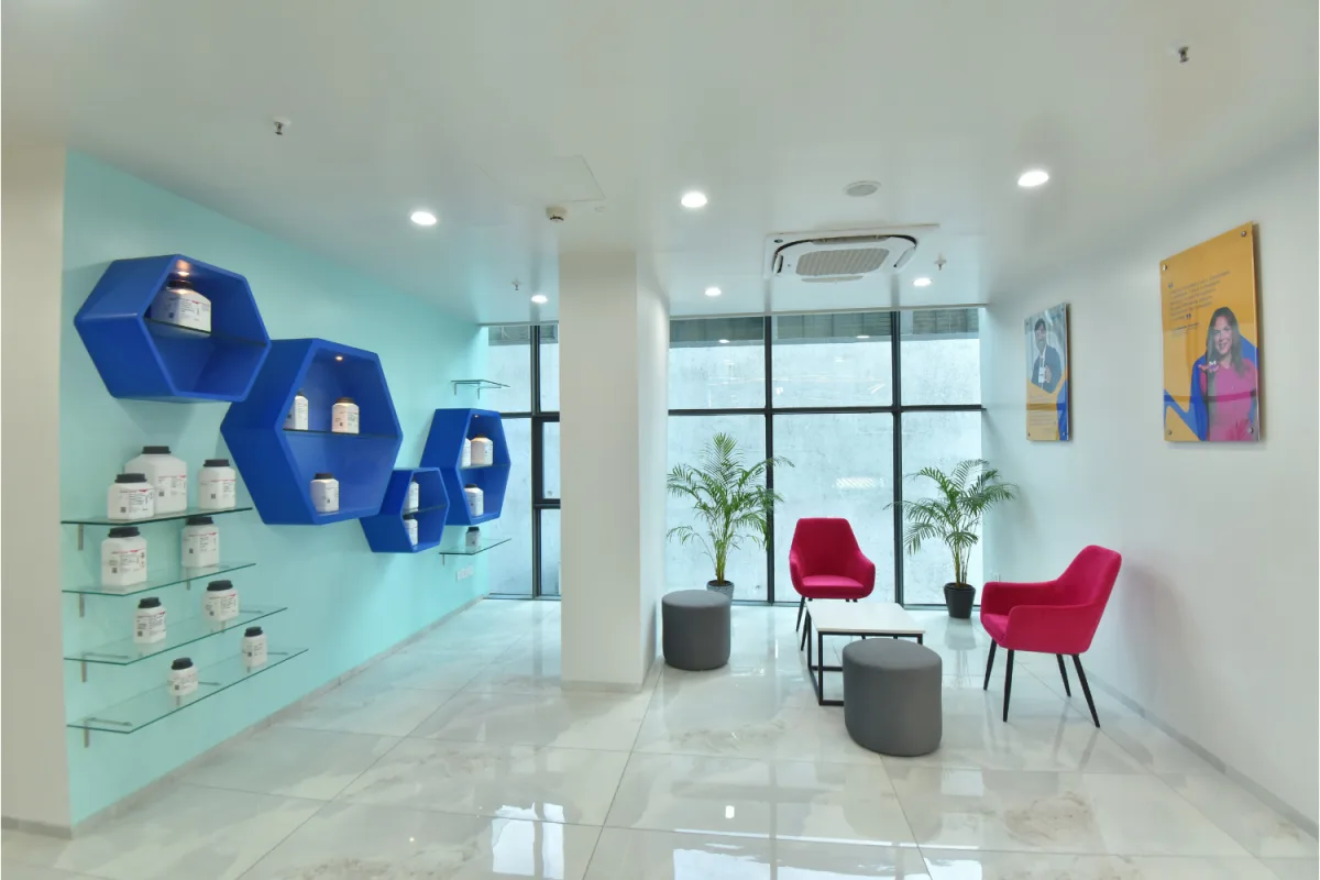 Lobby lounge with hexagonal product display, magenta chairs and grey poufs