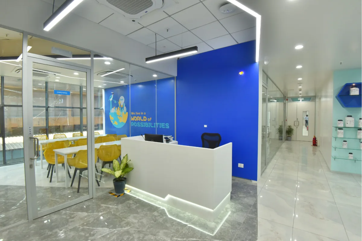 Reception desk beside glass-walled cafeteria with yellow chairs