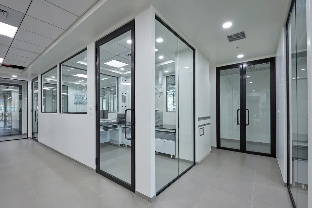 Glass-partitioned laboratory corridor with black-framed doors