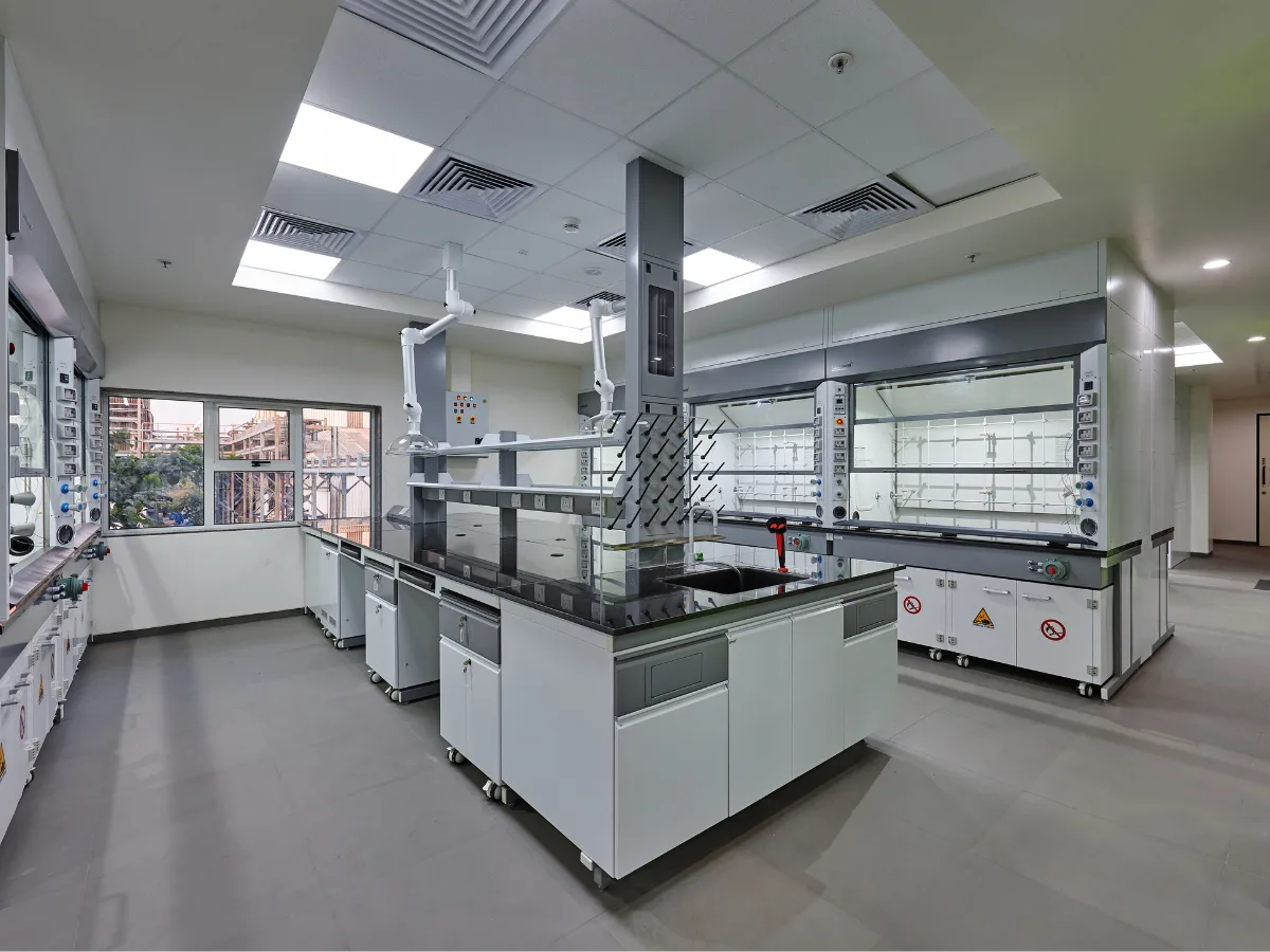 Wide lab with island bench, pegboard and wall-mounted fume hoods