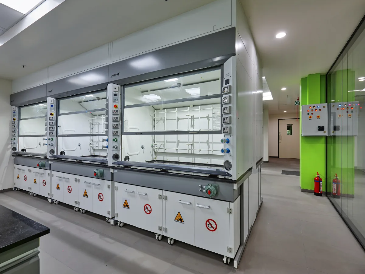 Row of fume hoods with hazard stickers and green accent wall