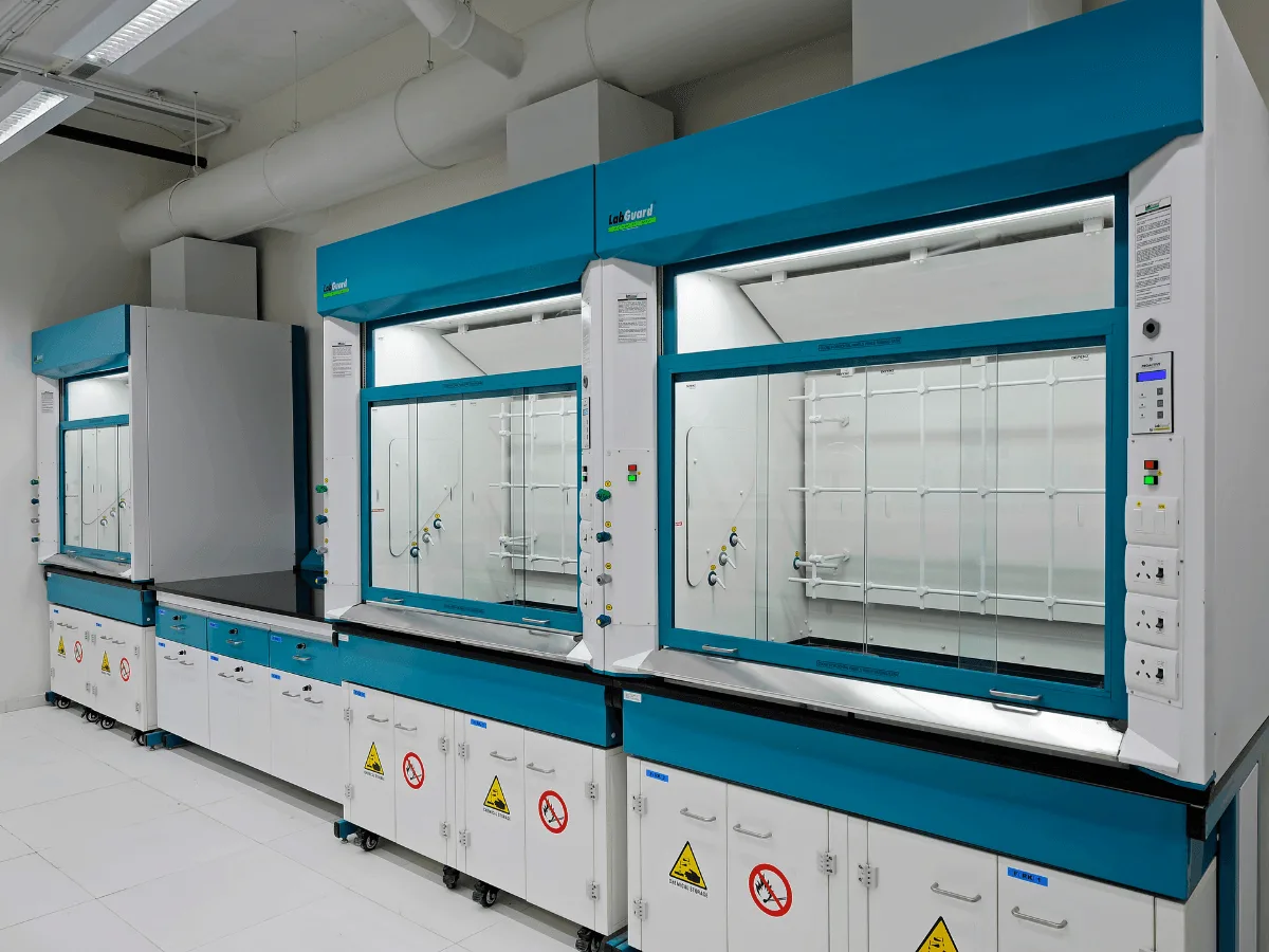 Row of blue fume hoods with glass sashes and hazard stickers