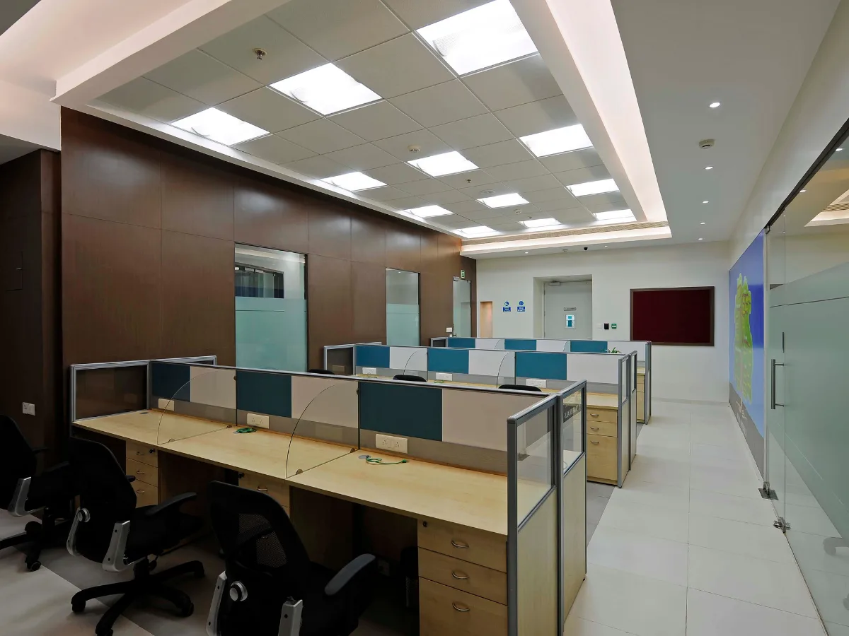 Office overview with dark wood paneling and teal cubicle dividers