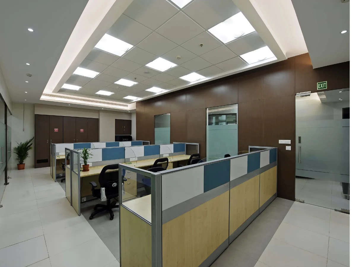 Open-plan workstations with teal cubicle panels and dark wood walls