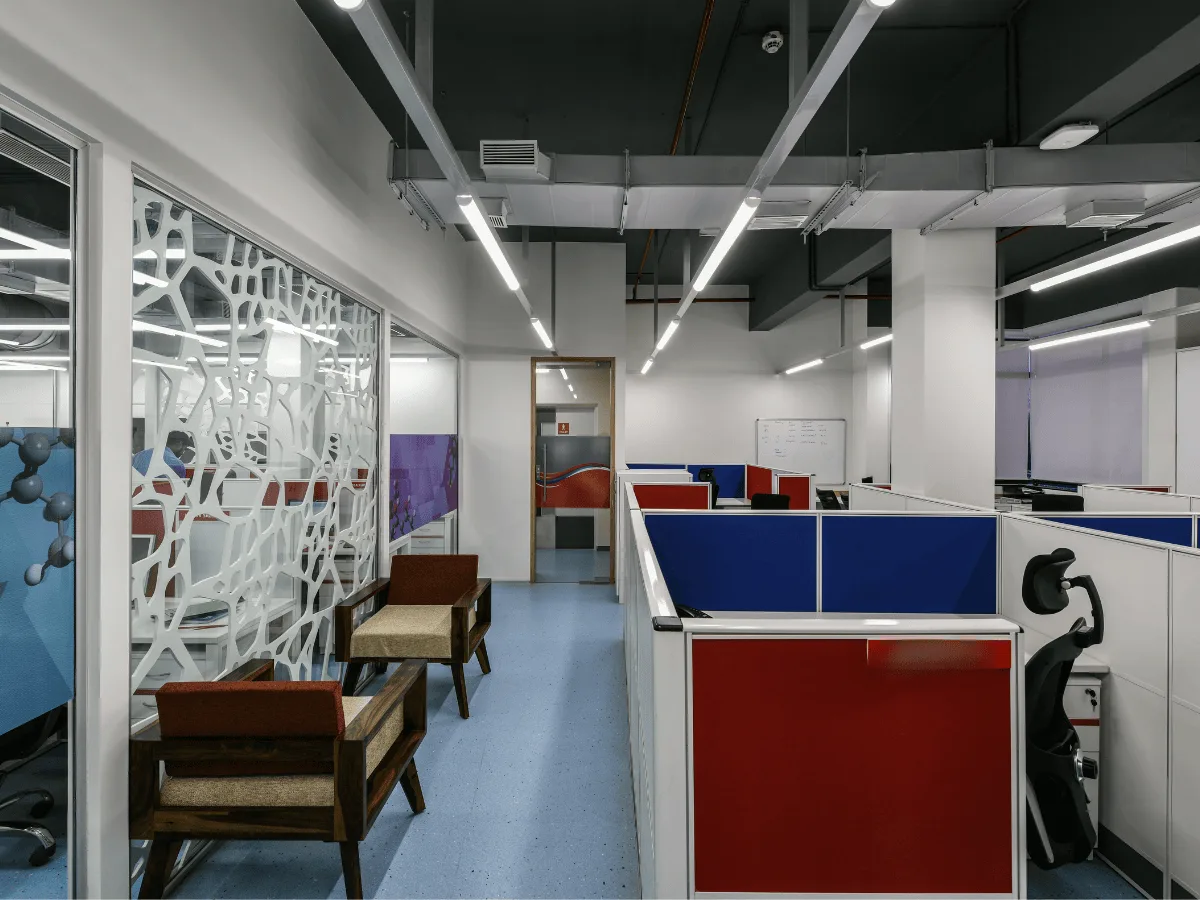 Workstations with blue and red panels, waiting chairs and molecule wall graphic