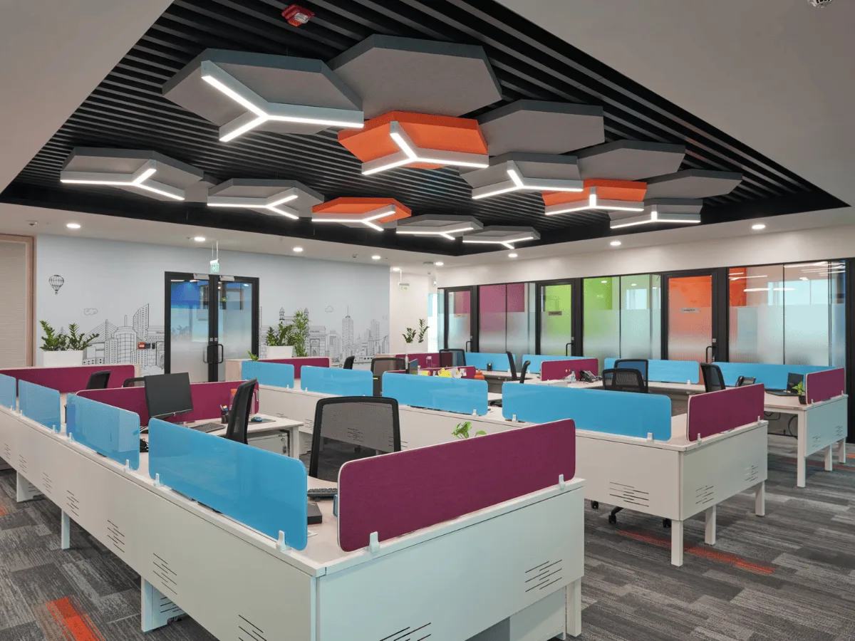Workstations with hexagonal ceiling baffles and colourful desk dividers