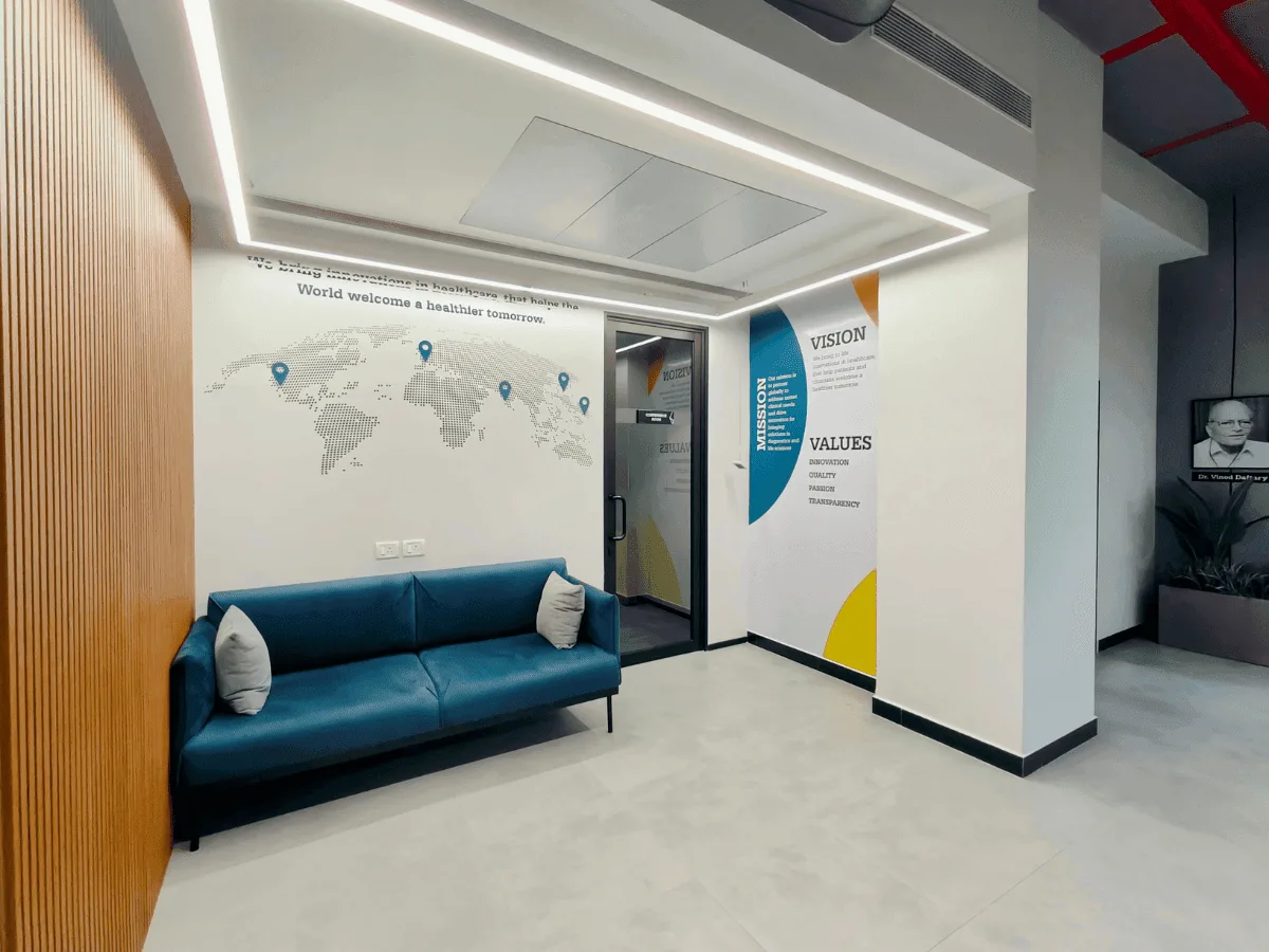 Breakout area with world map mural, teal sofa and vision-mission-values wall