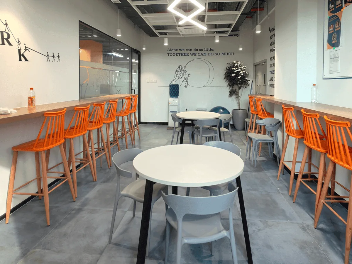 Pantry with orange bar stools, round tables and teamwork wall quotes