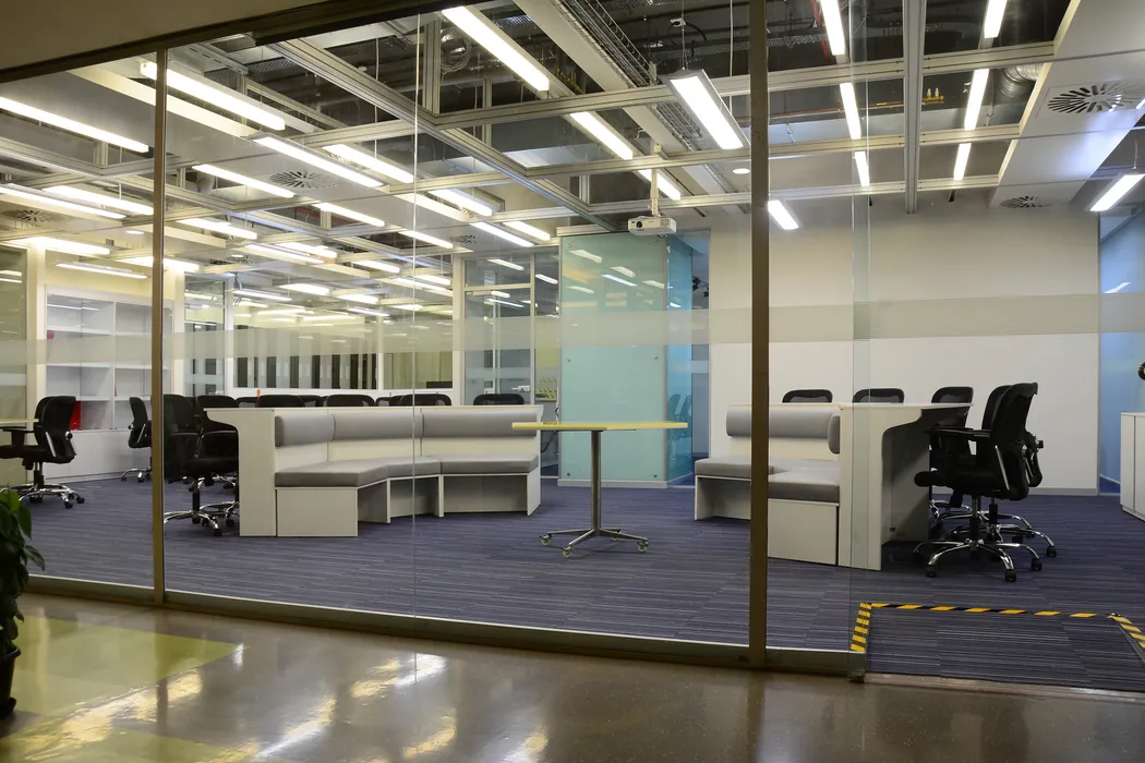 Collaborative office lounge with banquette seating viewed through glass partition