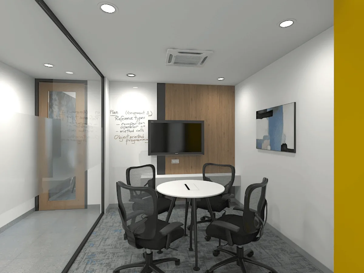 Small meeting room with round table, display screen, and whiteboard walls