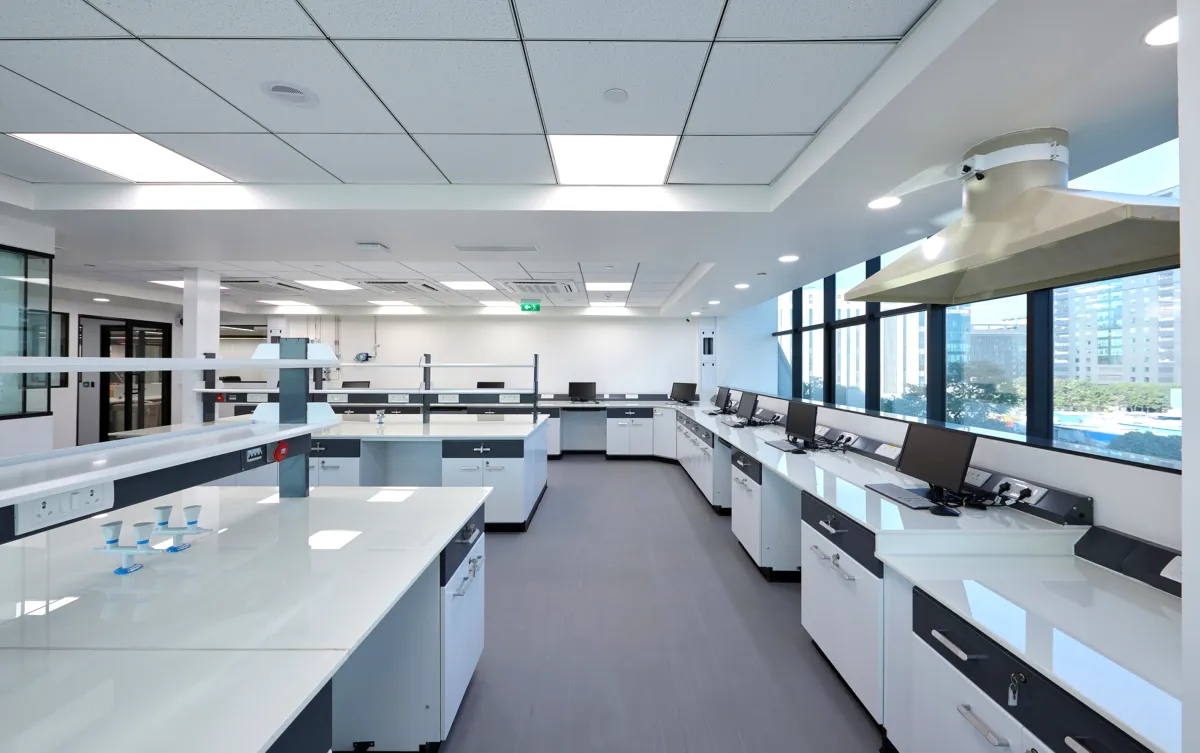 Wide lab with island benches, canopy hood and city skyline through windows